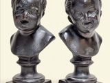 pair of bronze busts of children on pedestals on a white background