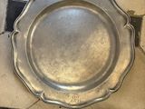a silver plate on the floor next to a brown dog