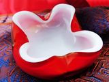 a red bowl with a white flower in it on a table