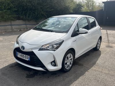 La Toyota Yaris est garée sur un parking devant un immeuble.