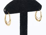 gros plan sur une paire de boucles d'oreilles en or sur un support noir