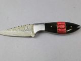a knife with a red handle on a white surface