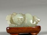 chinese carved jade figurine of a sleeping child on a wooden stand