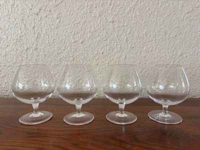 four empty wine glasses lined up on a table in front of a wall
