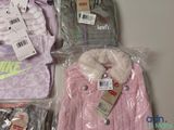 a pile of clothing that includes a pink jacket, a pink jacket, and a purple jacket