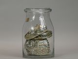 a glass jar filled with coins and shells on a table