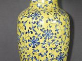 un vase jaune orné de fleurs bleues sur fond gris