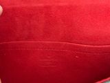 someone is holding a red and black purse with a red handle