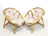 une paire de chaises en bambou avec des coussins à motifs dans une pièce blanche
