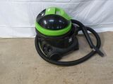 un aspirateur vert et noir posé sur le sol