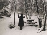 a black and white photo of a woman standing in the snow