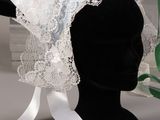 a black mannequin head with a white lace veil on it