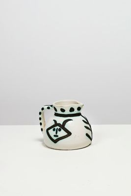 un vase blanc orné de motifs noirs et blancs, posé sur une table