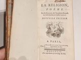 une main tenant un livre ouvert sur lequel figure l'image d'un oiseau