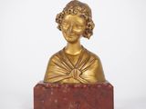 a gold statue of a woman on a red marble base