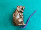 une petite souris en bronze posée sur une surface verte
