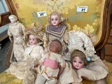 five dolls sitting on a chair with a yellow background
