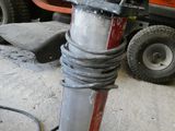 une borne d'incendie rouge et noire dans un garage, avec une tondeuse à gazon en arrière-plan