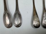four silver spoons are lined up on a white surface