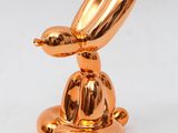 an image of a gold sculpture of a rabbit sitting on top of a plate