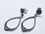 une paire de boucles d'oreilles noires et argentées sur fond blanc