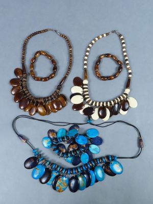 trois colliers et bracelets différents posés sur un fond gris