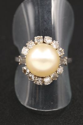 un gros plan d'une bague ornée d'une perle et de diamants