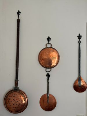 plusieurs casseroles et poêles en cuivre accrochées au mur d'une cuisine