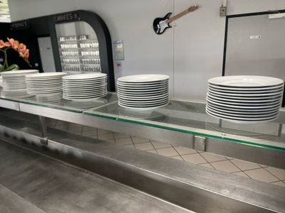 many white plates on a glass shelf in a kitchen