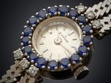 a close up of a wrist watch with blue sapphires and diamonds