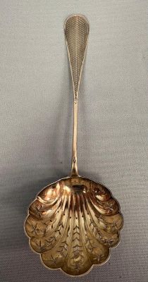 a silver spoon with a leaf shaped handle on it