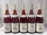 six bottles of wine are lined up in a row on a table