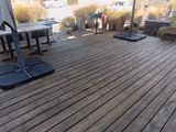 une terrasse en bois avec une table, des chaises et un parasol