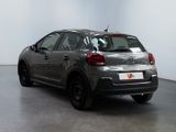 the back of a silver car is parked in a white room