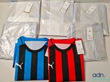 Plusieurs maillots de foot sont posés sur une table, dans des sacs en plastique