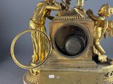 a gold clock with a boy and a girl on top of it