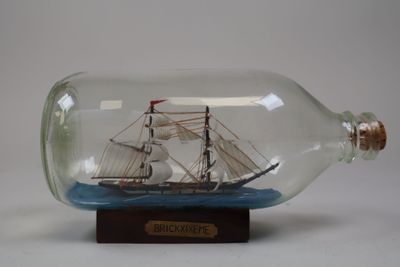un bateau dans une bouteille, posé sur un socle en bois