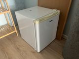 a small white refrigerator in the corner of a room