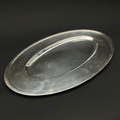 une assiette en argent posée sur une table noire, sur fond noir