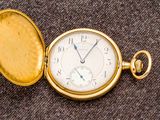une montre de poche en or posée sur une surface marron
