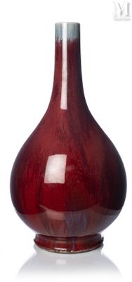 un vase rouge posé sur une surface blanche