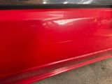 a close up of a red car door with a sticker on it
