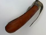 un vieux couteau avec un manche en cuir posé sur une surface blanche