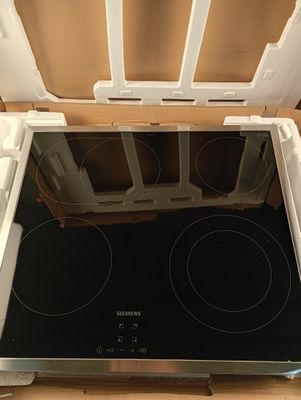 une boîte posée par terre, contenant une plaque de cuisson à l'intérieur