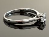 a close up of a diamond ring on a reflective surface