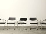 four black chairs are lined up against a white wall