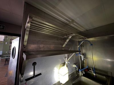 une cuisine équipée d'un évier en inox et d'une grande fenêtre