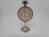 a silver clock on a stand on a white surface