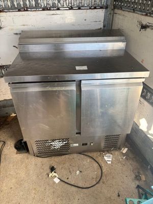 two stainless steel refrigerators sitting in a dirty room