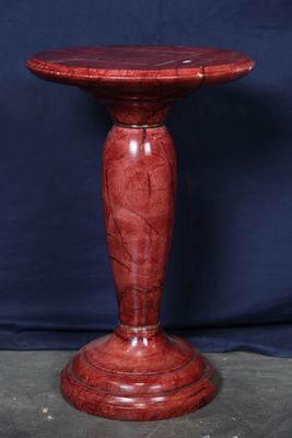 un socle en marbre rouge avec une base en bois sur fond bleu